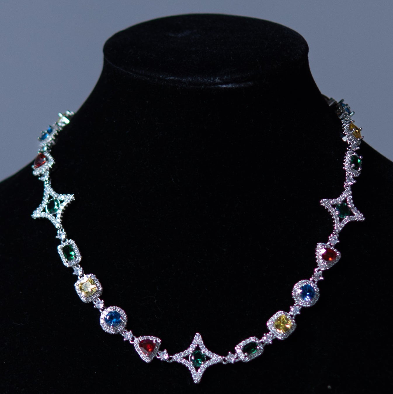 Multicolored gemstone necklace on a black mannequin against a gray background